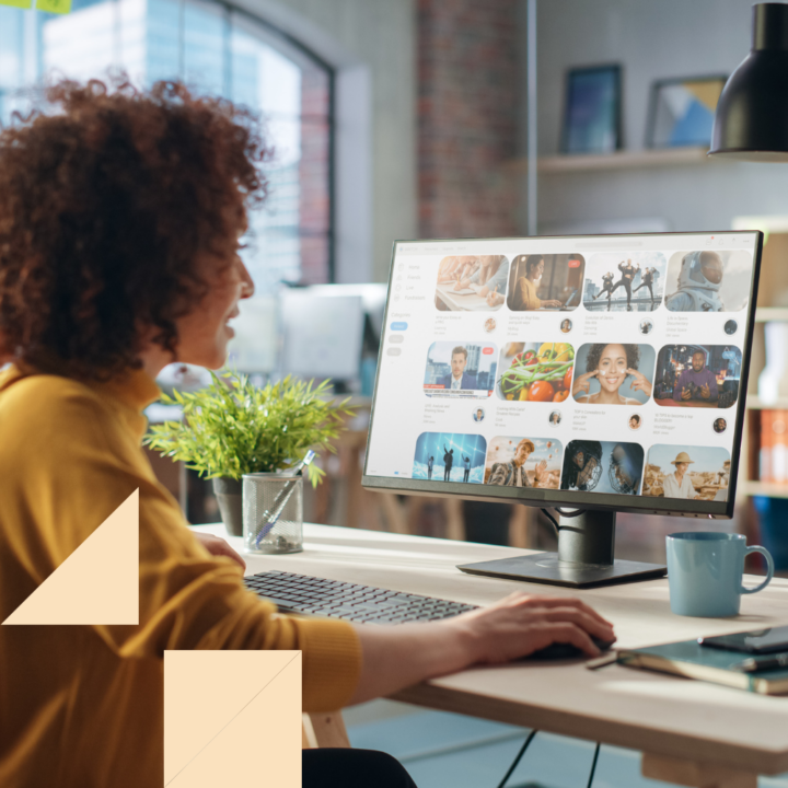 Social media manager working on a desktop computer, reviewing a visual content dashboard in a modern office setting