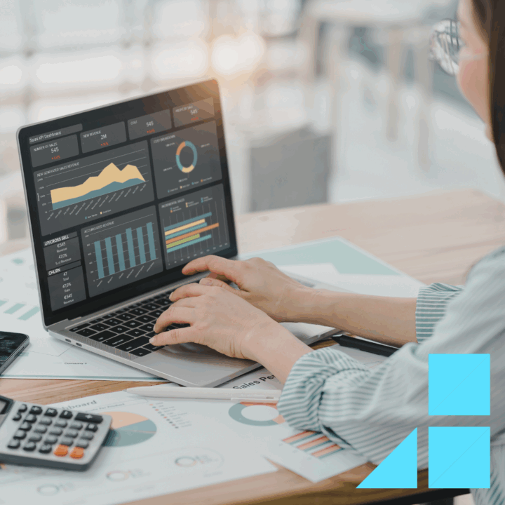 Data scientist analyzing business data on a laptop with interactive dashboards showing charts and graphs; financial documents, a calculator, and smartphone are on the desk, representing data analysis and reporting in a professional setting.