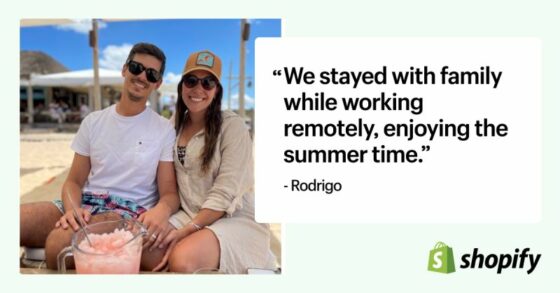 A couple sits smiling on a beach with drinks in hand, enjoying sunny weather. Next to the photo is a quote that reads, “We stayed with family while working remotely, enjoying the summer time.” – Rodrigo. The image includes the Shopify logo, highlighting remote work flexibility.