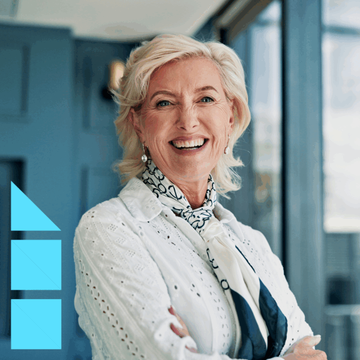 Confident female CFO smiling in a modern office setting with financial charts in the background, representing leadership and executive decision-making.
