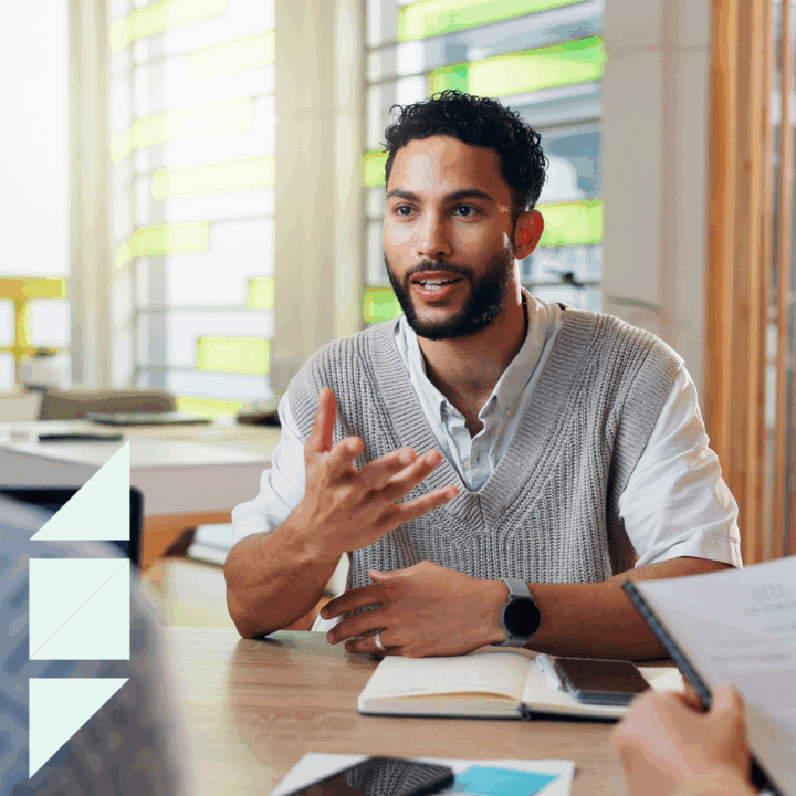 Hiring manager conducting a second interview with a candidate, taking notes while the candidate answers thoughtfully, representing professional interview process