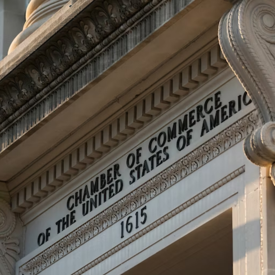 The exterior of a historic stone building shows an engraved sign reading “Chamber of Commerce of the United States of America,” with the year 1615 carved below decorative architectural details.