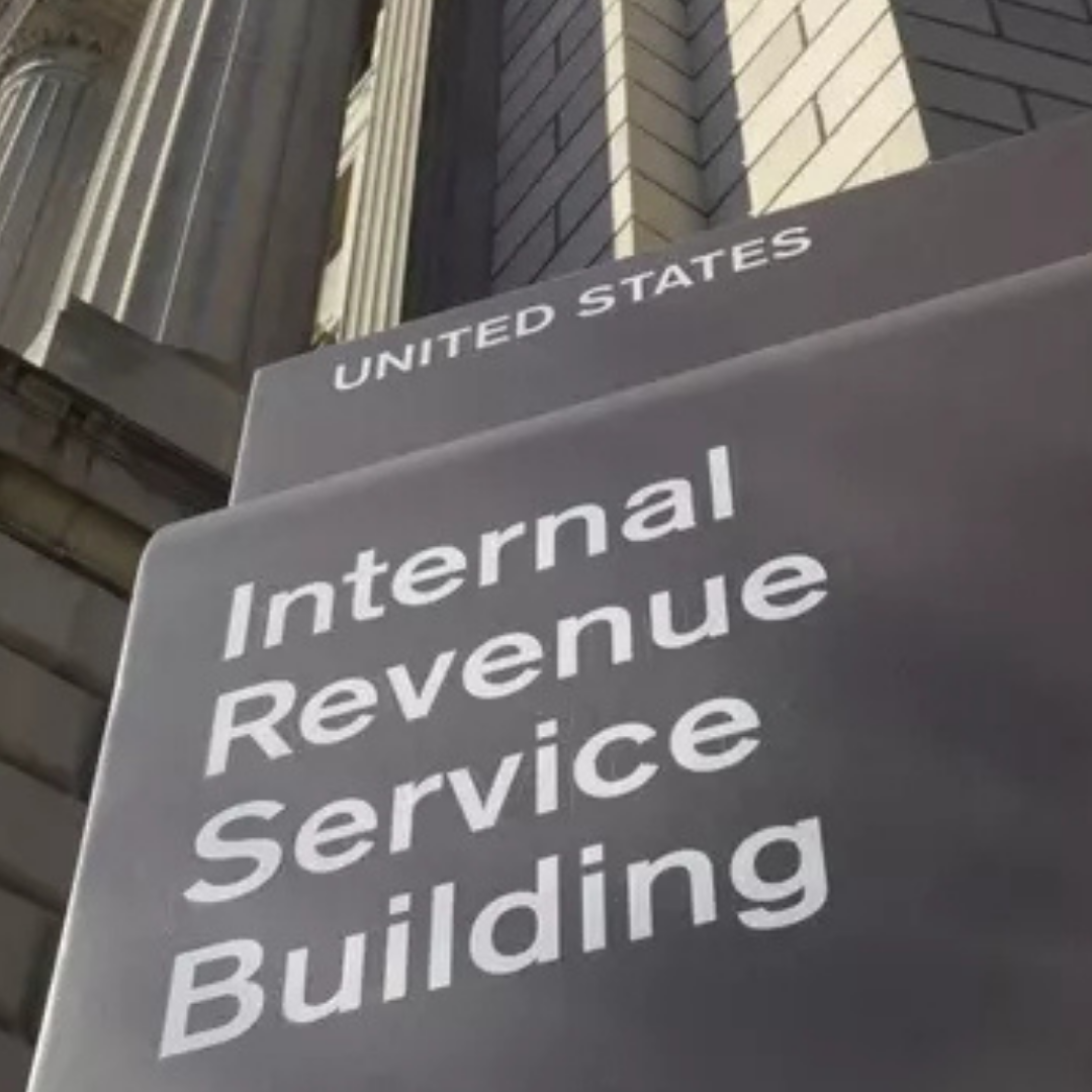 A sign reading “Internal Revenue Service Building” beneath the words “United States,” mounted on the exterior of a stone government building with tall columns.