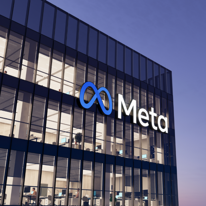 The exterior of a modern office building displays the Meta logo on a glass façade, with interior office spaces visible through large windows at dusk.