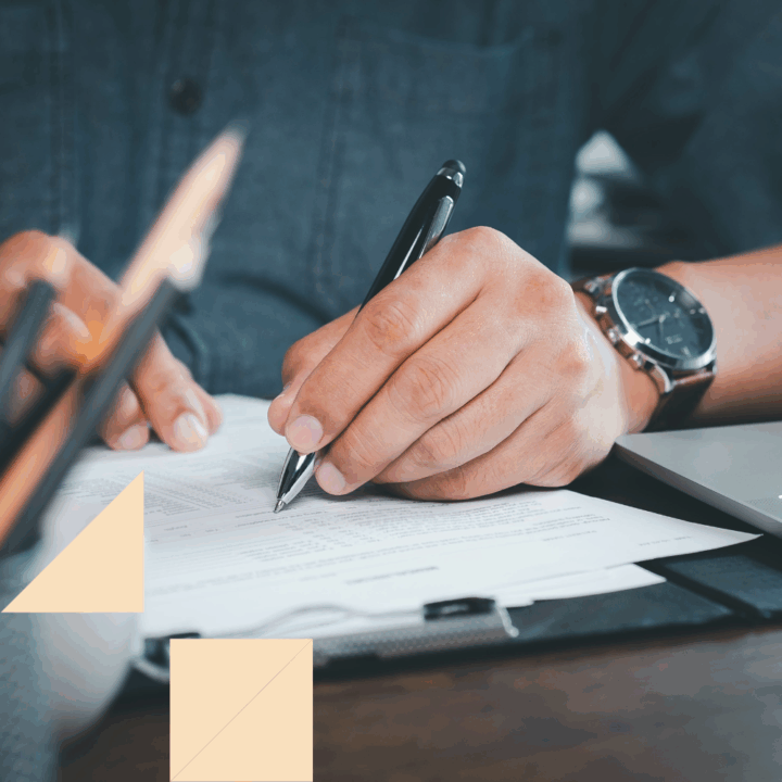 Close-up of a person filling out a pre-interview questionnaire at a desk, holding a pen with a watch on their wrist, symbolizing preparation and organization during the hiring process.
