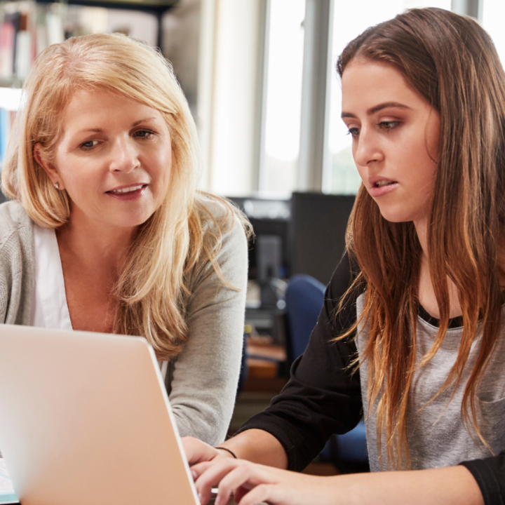 Mother and young woman working together at a laptop in a professional setting, representing career guidance, mentorship, and rethinking education or career paths.