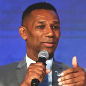 Professional speaker holding a microphone during a conference or panel discussion, representing workplace leadership, HR topics, and discussions around employment practices.