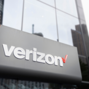 Verizon logo on the exterior of a modern office building, with glass windows and a city backdrop, representing corporate operations or workforce changes.