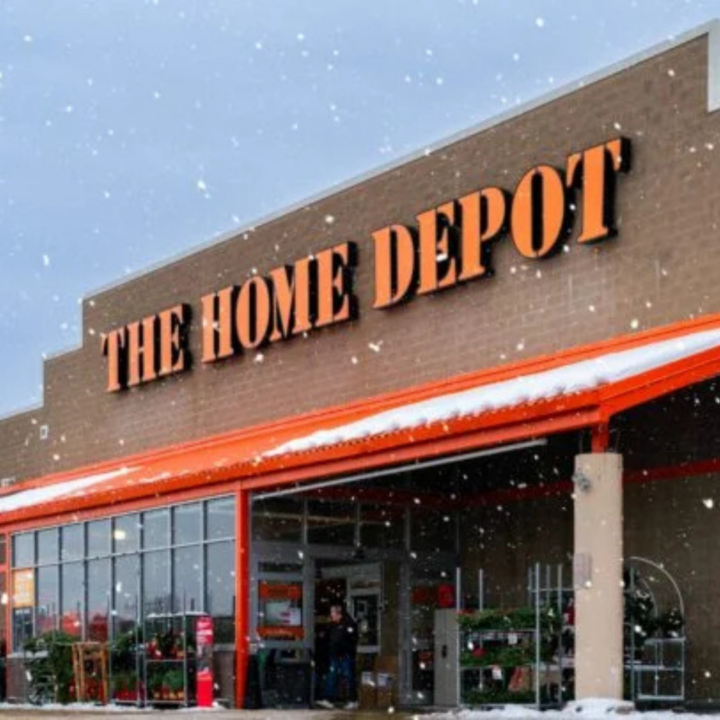 Exterior of a Home Depot store during snowfall, with the orange “The Home Depot” sign displayed above the entrance.