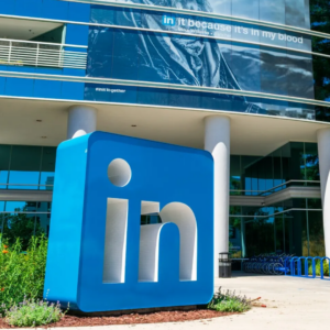 Large LinkedIn logo displayed outside a modern office building, representing the professional networking platform and corporate workplace environment.