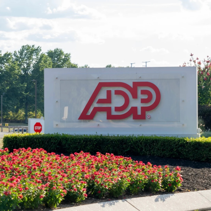 Large ADP logo sign outside a corporate office campus, surrounded by landscaping and flowers.