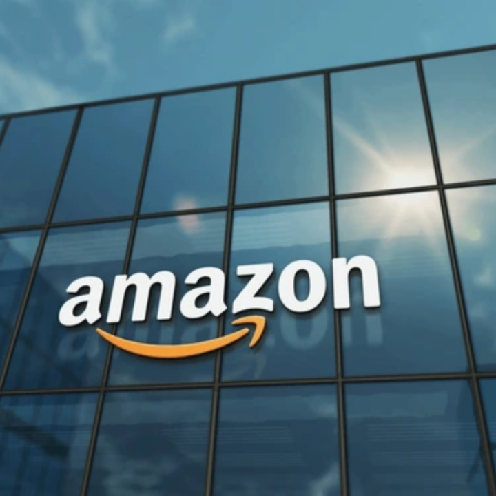 Amazon logo displayed on the exterior of a modern glass office building with sunlight reflecting off the windows