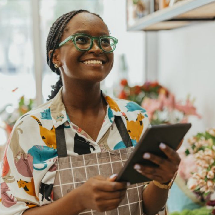 Small business owner smiling while holding a tablet in a shop
