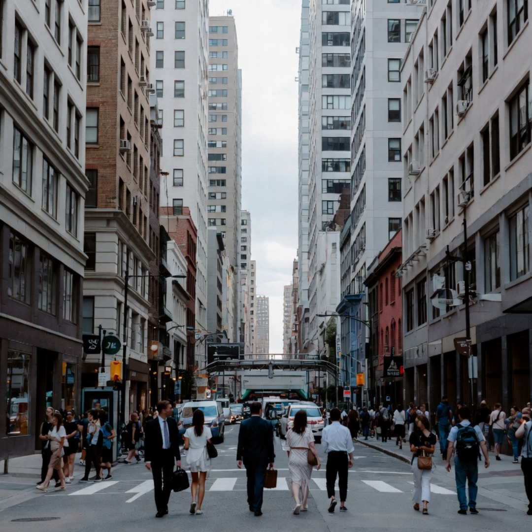 Busy downtown city street with pedestrians and commuters walking between tall office buildings
