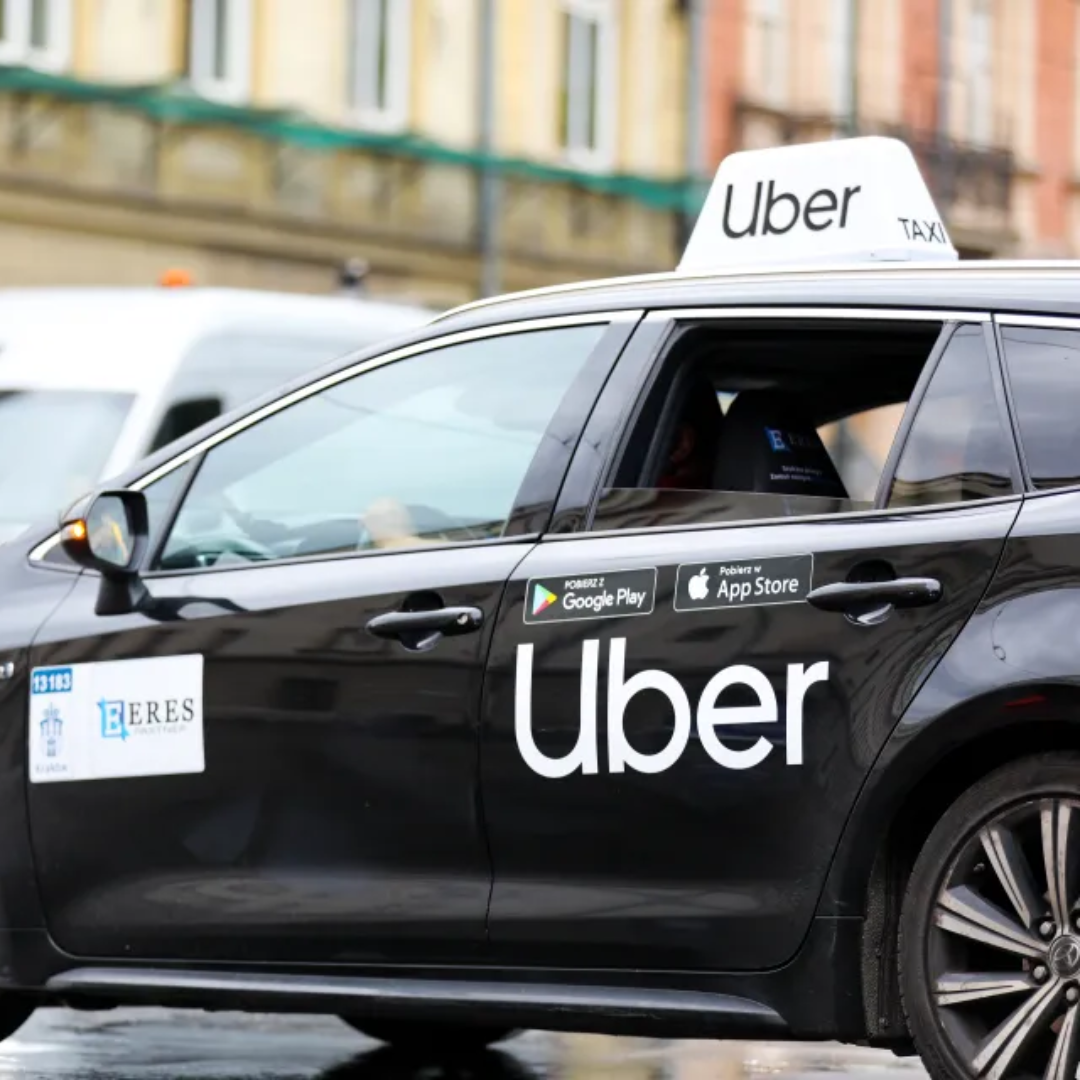 Black Uber taxi vehicle with branded signage on the door and roof light on a city street