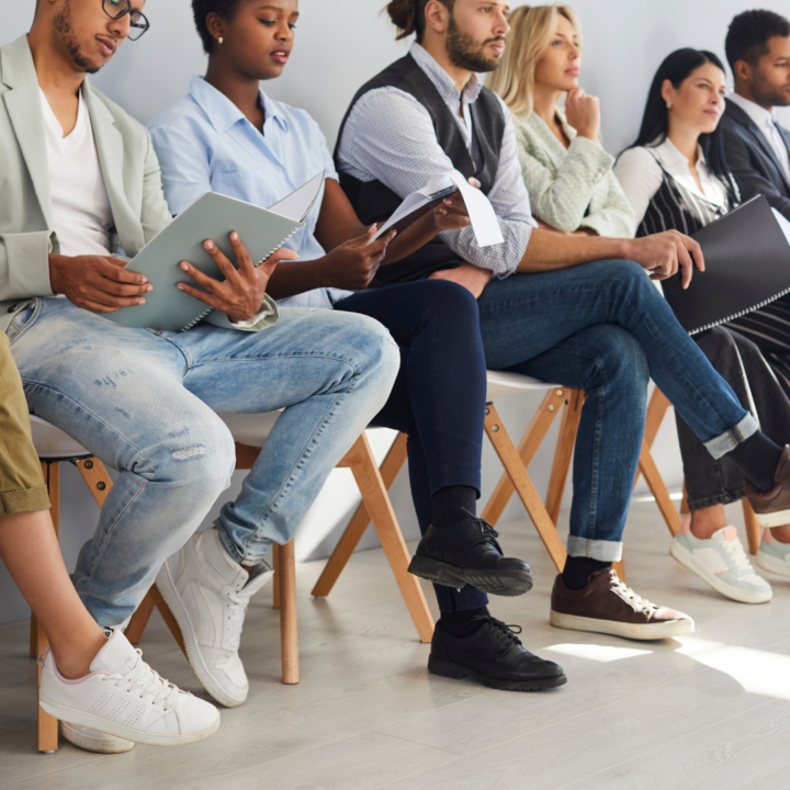 Job applicants sit on chairs in row waiting for interview
